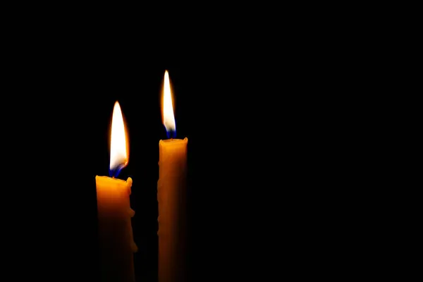 两个燃烧的蜡烛在黑暗中 在黑色背景上燃烧黄色蜡烛 并留有复制空间 图库图片
