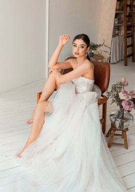 Şatafatlı bir gelin, modern bir gelinlik içinde, sabahları kendi iç mekanında.