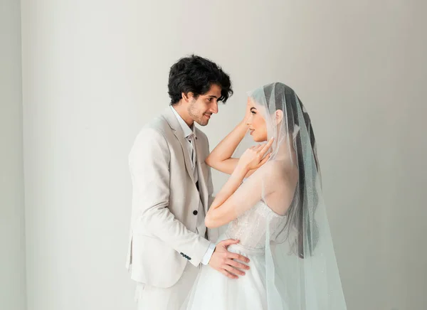 Noiva em vestido branco e noivo em terno, posando em apartamento branco — Fotografia de Stock