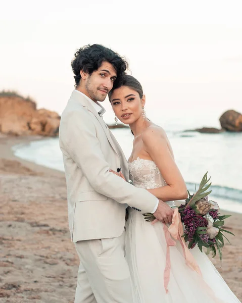 Casal de casamento de moda, noivo e noiva em vestido de noiva perto do mar à beira-mar — Fotografia de Stock