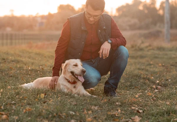 Handsome man with a dog golden retriever walk in spring meadow — Stock Photo, Image