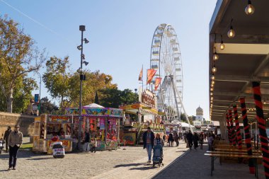 Sevilla (Endülüs, İspanya) 'daki Sevilla Noel Fuarı' nda gıda tezgahları ve panayır yerleri. Güneşli bir kış gününde insanlar dev bir dönme dolabın yanında yürüyorlar..