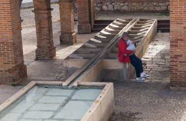 Yaşlı adam Aracena 'da (Huelva, İspanya) eski bir umumi çamaşırhanenin yanında uyuyan bir bebeği kucağında tutar.).