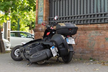 Yerde elektrikli kiralık motosiklet var. İki kiralık motosiklet, biri caddeye düşmüş. Vandalizm sonucu motosiklet yere düştü..
