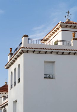 Akdeniz tarzında iki katlı bir evin cephesi. Bir yerleşim yerindeki beyaz duvarlı evin dış görünüşü.