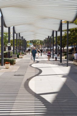 Torremolinos 'un (Endülüs, İspanya) ana güvertesine gölge düşürmek için Pergola. İnsanlar güzel bir pergola ile dekore edilmiş ana caddede şehir merkezinde geziniyorlar..