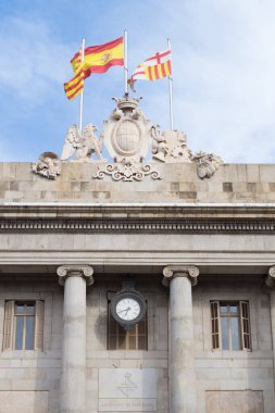 Flags of Catalonia, Spain and Barcelona flying over Barcelona City Hall. Neoclassical and gothic faade with Barcelona City Council in Catalan.