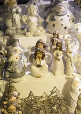 Rafta bir sürü seramik melek ve kardan adam var. Dikey görünüm