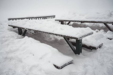 Winter landscape - a big green table and benches in the snow. 