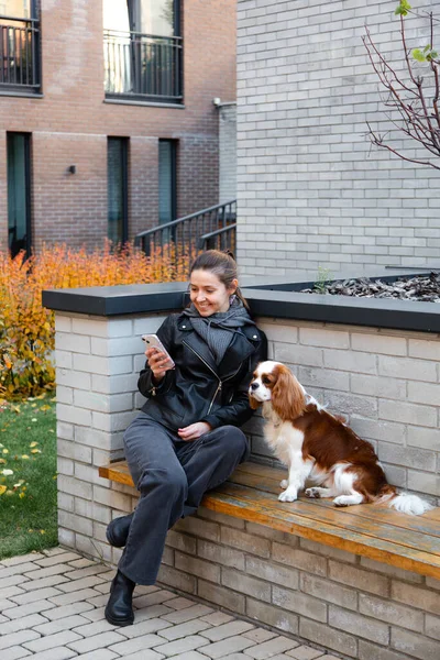 Junge Frau Sitzt Auf Der Bank Mit Dem Hund Cavalier — Stockfoto