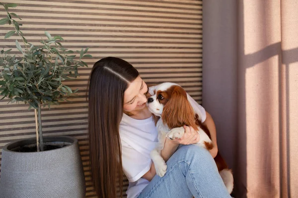 Junge Frau zu Hause lächelt mit Cavalier King Charles Spaniel Hund. — Stockfoto