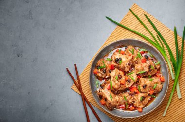 Dim Sum Pork Spare Ribs or Pai Guat in gray bowl on dark concrete table top. Chinese cantonese cuisine steamed spareribs dish with black soybeans. Asian food. Top view. Copy space