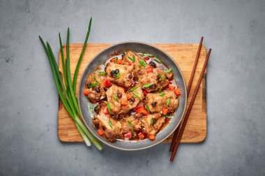 Dim Sum Pork Spare Ribs or Pai Guat in gray bowl on dark concrete table top. Chinese cantonese cuisine steamed spareribs dish with black soybeans. Asian food. Top view