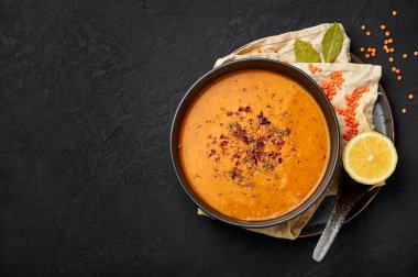 Ezogelin Soup in black bowl on dark slate table top. Turkish cuisine traditional dish with red lentils, bulgur and rice. Copy space