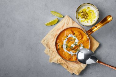 Murgh Makhani or Butter Chicken in copper bowl on gray concrete table top. Indian Cuisine dish with chicken meat and creamy masala. Asian food and meal. Copy space. Top view
