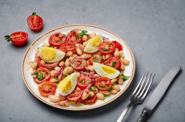 A Piyaz salad on white plate on gray concrete table top. Turkish cuisine vegetarian dish. Middle eastern cuisine food.