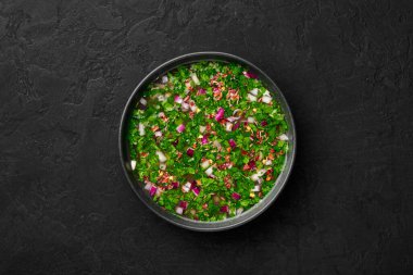 Pachi Pulusu in black bowl on dark slate table top. Raw Tamarind Rasam is indian cuisine soup dish. Asian food and meal. Top view