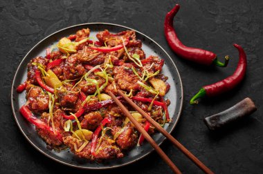 Kkanpunggi or Korean Spicy Garlic Fried Chicken on black plate on dark slate table top. Kan Pung Gi is korean and chinese cuisine dish. Typical asian food and meal.