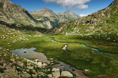 Majestic mountains landscape with river, rocky hills and green grassy valley. Beautiful wild nature