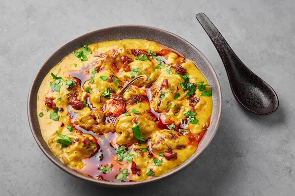 Punjabi Kadhi Pakora in gray bowl on concrete table top. Kadhi Pakoda is indian cuisine curry dish. Asian food and meal
