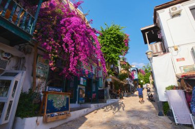 Kas, Turkey - 08 June 2022. Kas town cozy street. Overgrown with flowers Turkish village blooming street. Shop in Kas