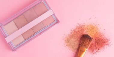 Gül arka planındaki makyaj fırçası ve pudra göz farı modelleme paleti 