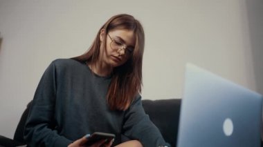 Girişimci genç kızıl saçlı, evde dizüstü bilgisayarla çalışıyor, bir telefon alıyor, cevap veriyor ve iş stratejisini dizüstü bilgisayarını işaret ederek tartışıyor. Koyu yeşil bir bluz giymişti