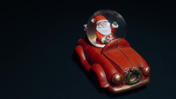 Ретро-автоіграшка, червона, з Сантою за кермом і подарунками в багажнику. Іграшки для дітей, зимова концепція. Різдво й Новий рік — стокове відео