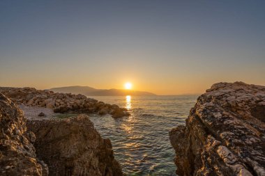 Arnavutluk 'taki Rocky Stone plajında gün batımı. Adriyatik denizi, Karaburun yarımadası ufukta