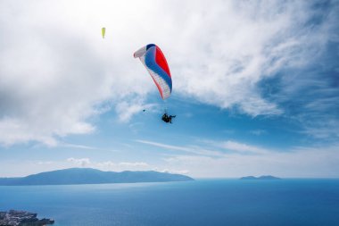 Bir yaz günü bulutlu bir gökyüzünün arka planında yamaç paraşütü yapan bir sporcu..