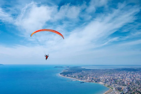 Bir yaz günü bulutlu bir gökyüzünün arkaplanına paraşütle atlayan bir sporcu. Arnavutluk