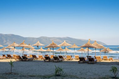 Güneşin kumsaldaki şemsiyeleri ve kumsalda güneşlenirler.