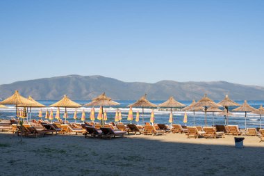 Güneşin kumsaldaki şemsiyeleri ve kumsalda güneşlenirler.