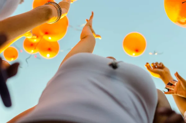 People Releasing Orange Balloons Blue Sky — Stockfoto