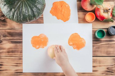 Adım adım Cadılar Bayramı çocukları özel balkabağı elması baskıları. 8. adım: Çocuk eli kağıda elmanın yarısı turuncu guaj boyasıyla boyanmış izler bırakır. Üst görünüm