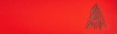 Kırmızı arka planda, Noel ağacı şeklinde uzanmış, altın sarısı kendi kendine dokunan vidalar. Pankart. Boşluğu kopyala