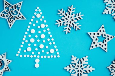 Beyaz yuvarlak haplar, açık mavi arka planda tahtadan kar taneleri olan Noel ağacı şeklinde serilmiş. Düz yatıyordu