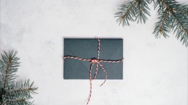 Beyaz arka planda, içinde Noel ağacı dalları olan yeşil zarfın olduğu hareket videosunu durdur. Boşluğu kopyala