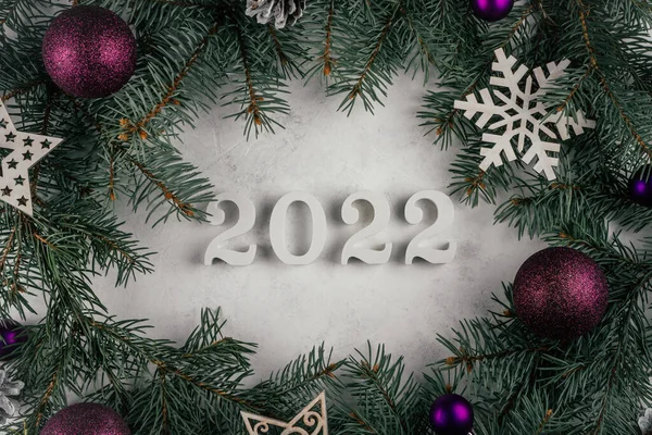 2022年白色木制数字躺在白色混凝土表面上 有圣诞树树枝 圣诞树装饰和紫色球 圣诞快乐 祝2022年新年快乐 顶部视图 — 图库照片