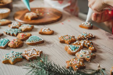 Kısmen bulanık çocuklar mutfaktaki ahşap masanın üzerine mavi ve beyaz kremalı zencefilli kurabiye süslediler. Çocuklar kurabiye hazırlar. Mutlu Noeller, mutlu yıllar.