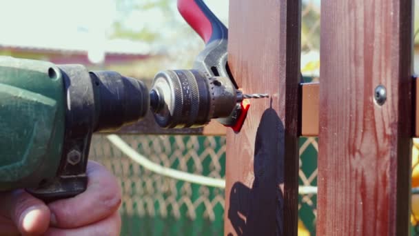 Férfi kéz fúró furattal lyuk csavar a barna kerítés fórumon, hogy javítsa meg. Lassított felvétel közeli videó — Stock videók