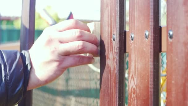 Чоловіча рука вставляє блок деревини між коричневими дошками паркану для вимірювання рівної відстані — стокове відео
