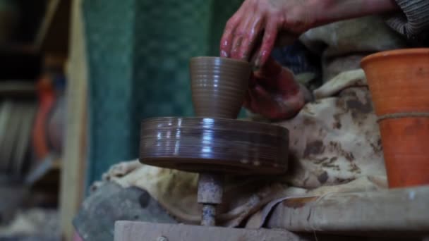 Manos de alfarero haciendo olla de arcilla en la rueda de alfarero manual con tracción a pie. Fabricación de cerámica artesanal — Vídeo de stock