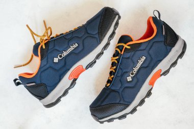 Mavi, turuncu ve gri sıcak kış ya da beyaz yüzeyde yatan Columbia markasının sonbahar spor ayakkabıları. Minsk, Belarus 30.10.2021