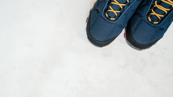 白いコンクリートの表面にオレンジの靴のレースと青い暖かい冬や秋のスニーカー、トップビュー。コピースペース。平敷 — ストック写真