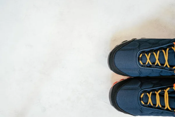 白いコンクリートの表面にオレンジの靴のレースと青い暖かい冬や秋のスニーカー、トップビュー。コピースペース。平敷 — ストック写真
