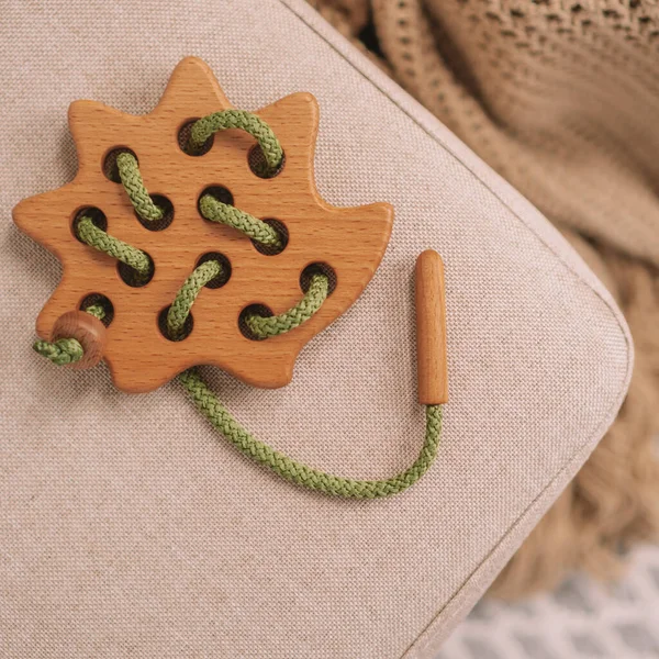Dětská dřevěná hračka s otvory pro výuku šněrování zelenou šňůrou na béžové lavičce. Horní pohled. Instagram čtvercového rámce — Stock fotografie