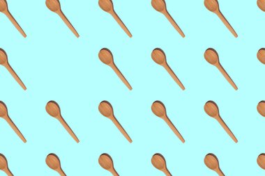 Katı gölgeli tahta kaşıklar, açık mavi arka planda izole edilmiş, kopyalama alanı. Üst görünüm