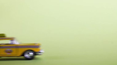 A yellow toy taxi car on a pastel yellow background drives into the frame and stops. Taxi service.