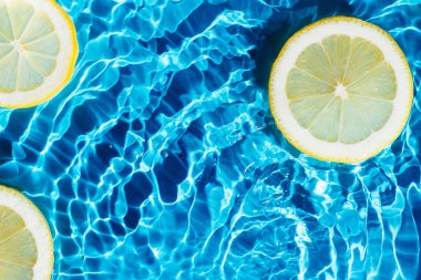 Şeffaf taze neşe veren su, arkaplanı benekli, limon dilimleri. Sağlıklı beslenme kumsalı. Düz yatıyordu